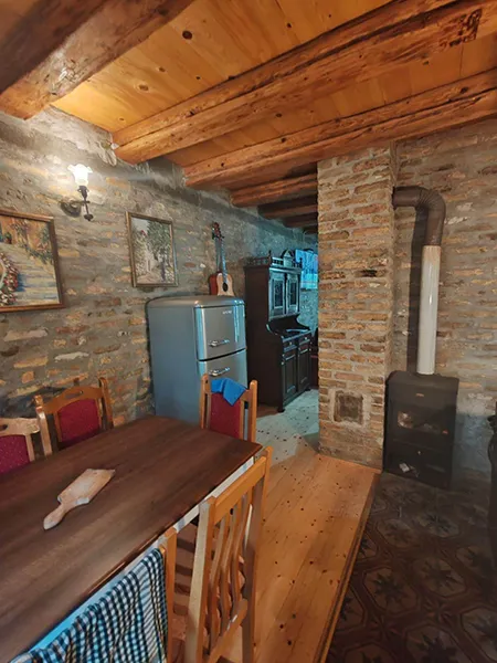 slika kuhinje na kojoj su frižider, peć na drva i trpezarijski sto