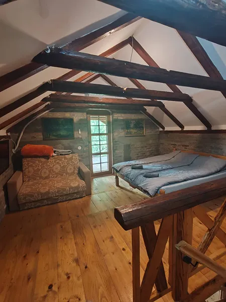 soba u potkrovlju na kojoj se vidi bračni krevet, dvosed i vrata za izlazak na terasu