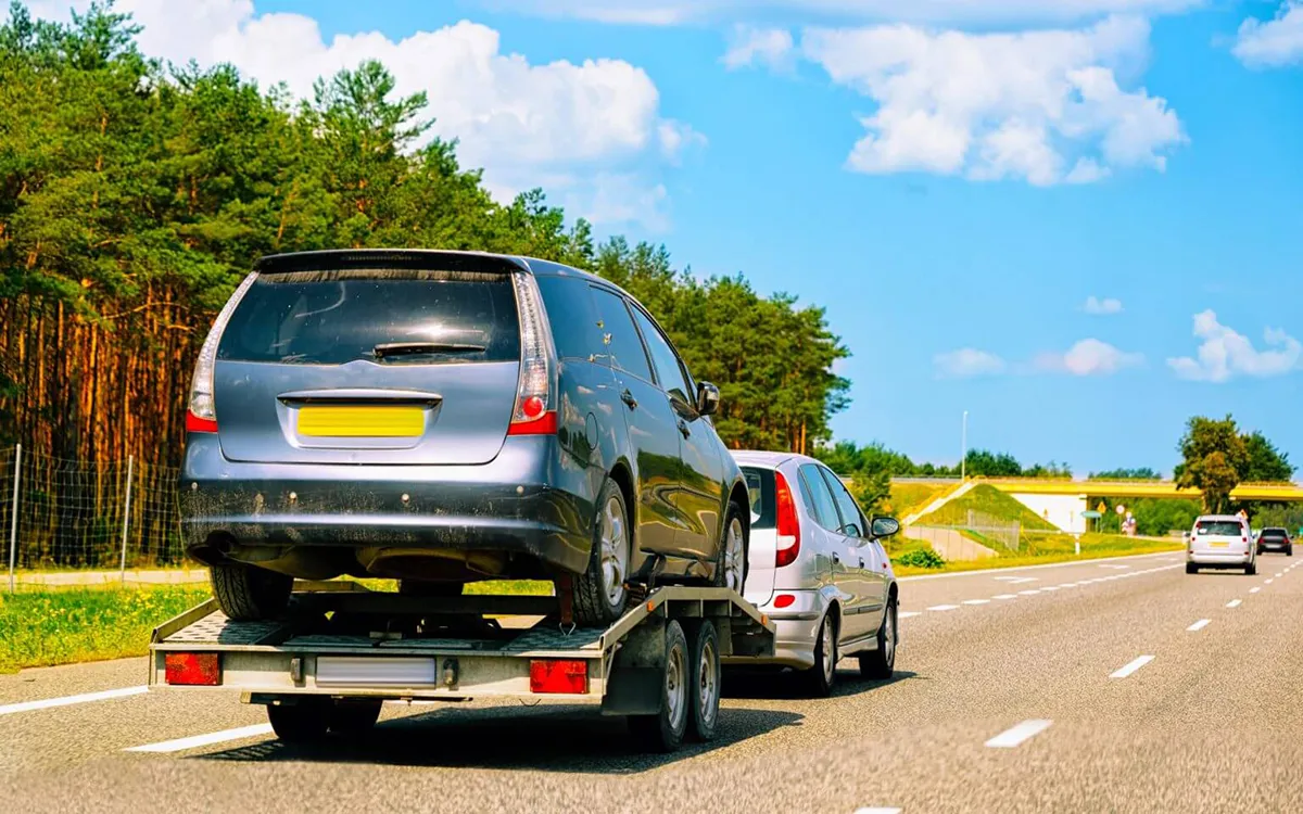 auto vuče drugi auto na prikolici