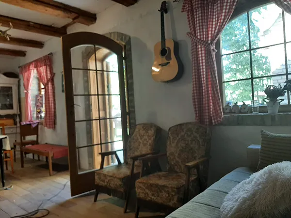 enterijer na kome se vide dve fotelje, akustična gitara, prozor i ulaz